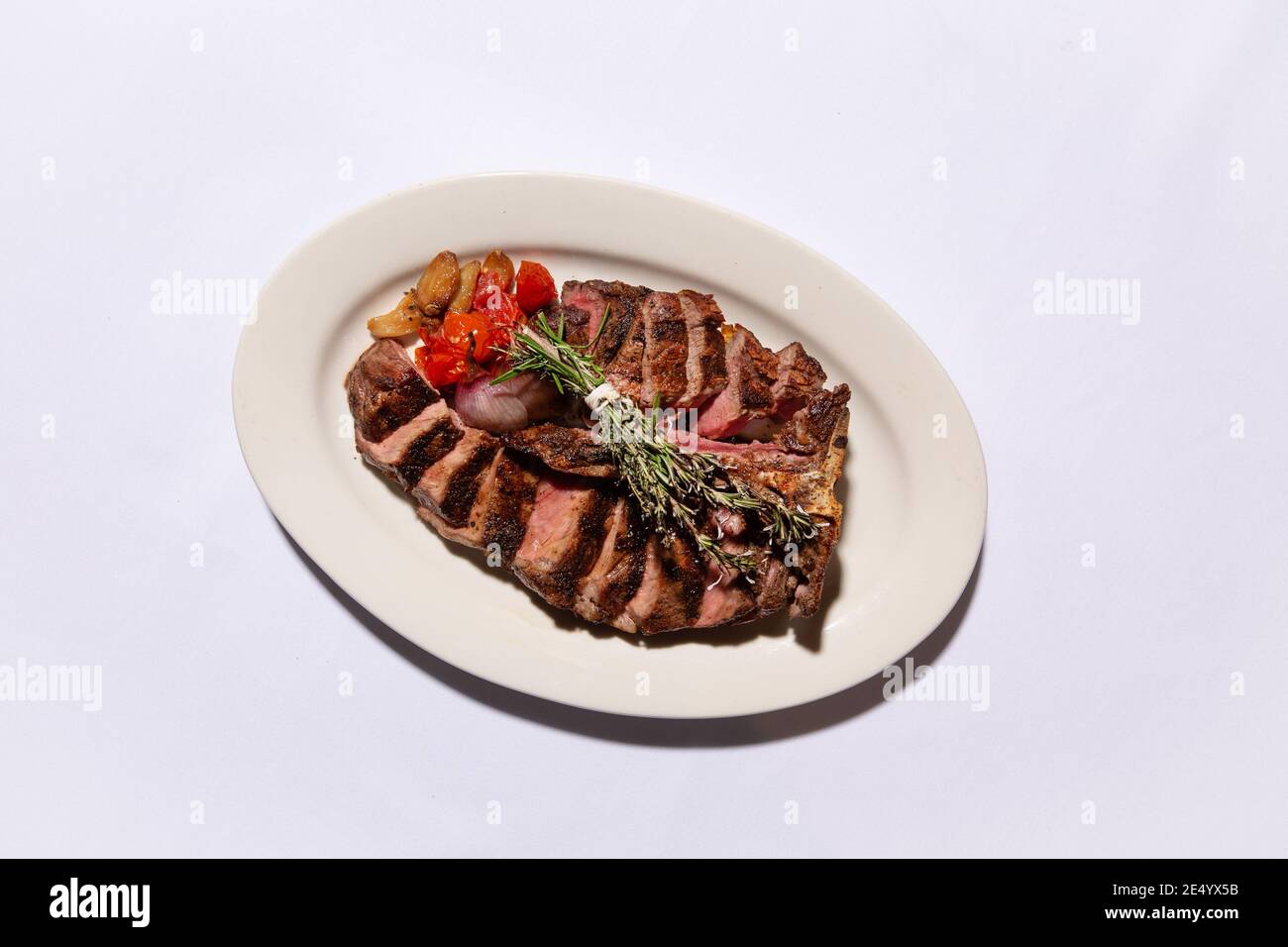 High Angle View of Sliced Bone-in Steak with Rosemary Stock Photo