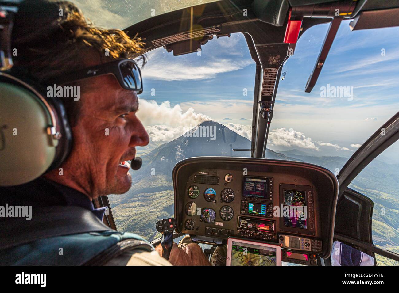 Helicopter pilot in his cockpit in front of the volcanoes of Bougainville, Papua New Guinea Stock Photo