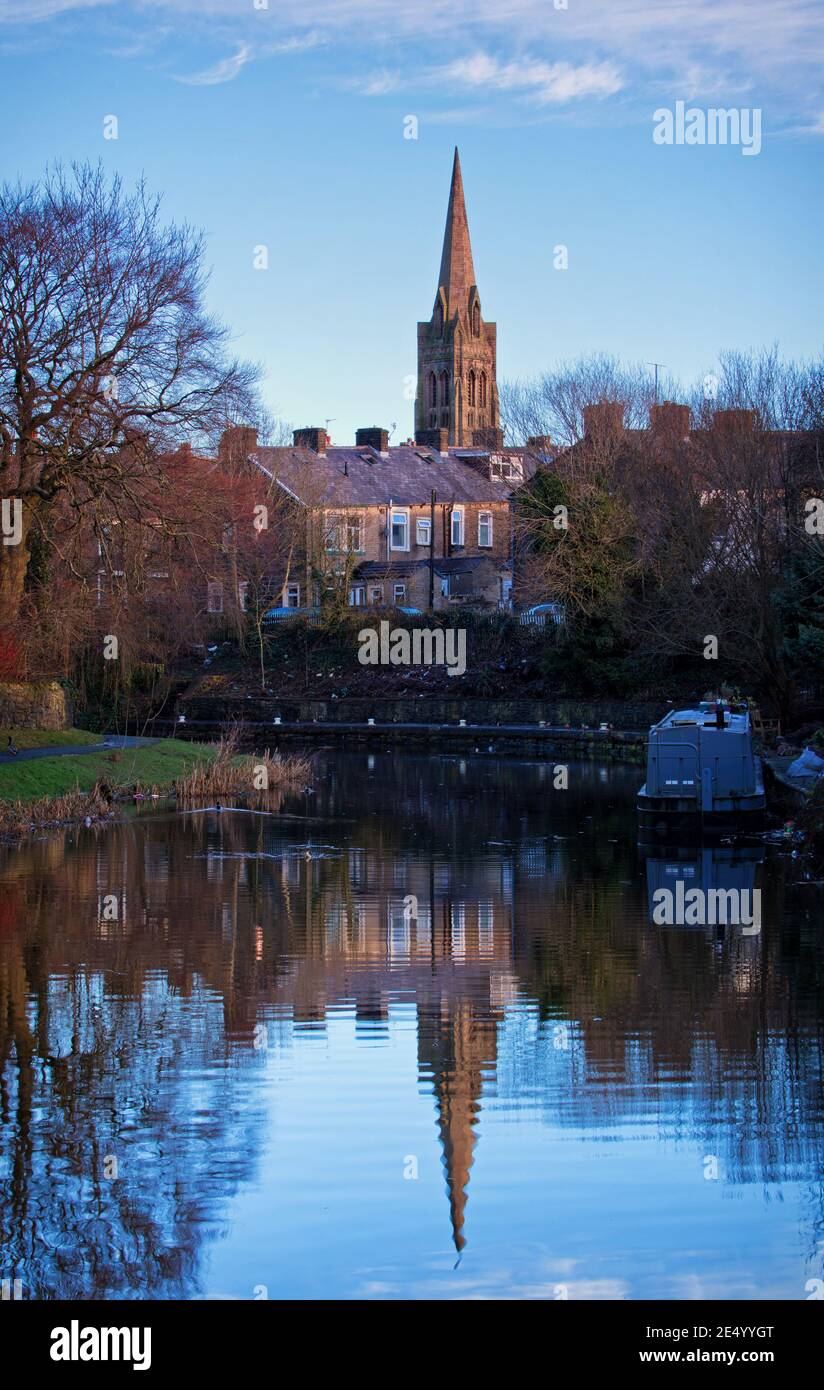 A distant St Mary's Church, with the shape of its spire reflected in the Leeds and Liverpool Canal, Nelson, Lancashire Stock Photo