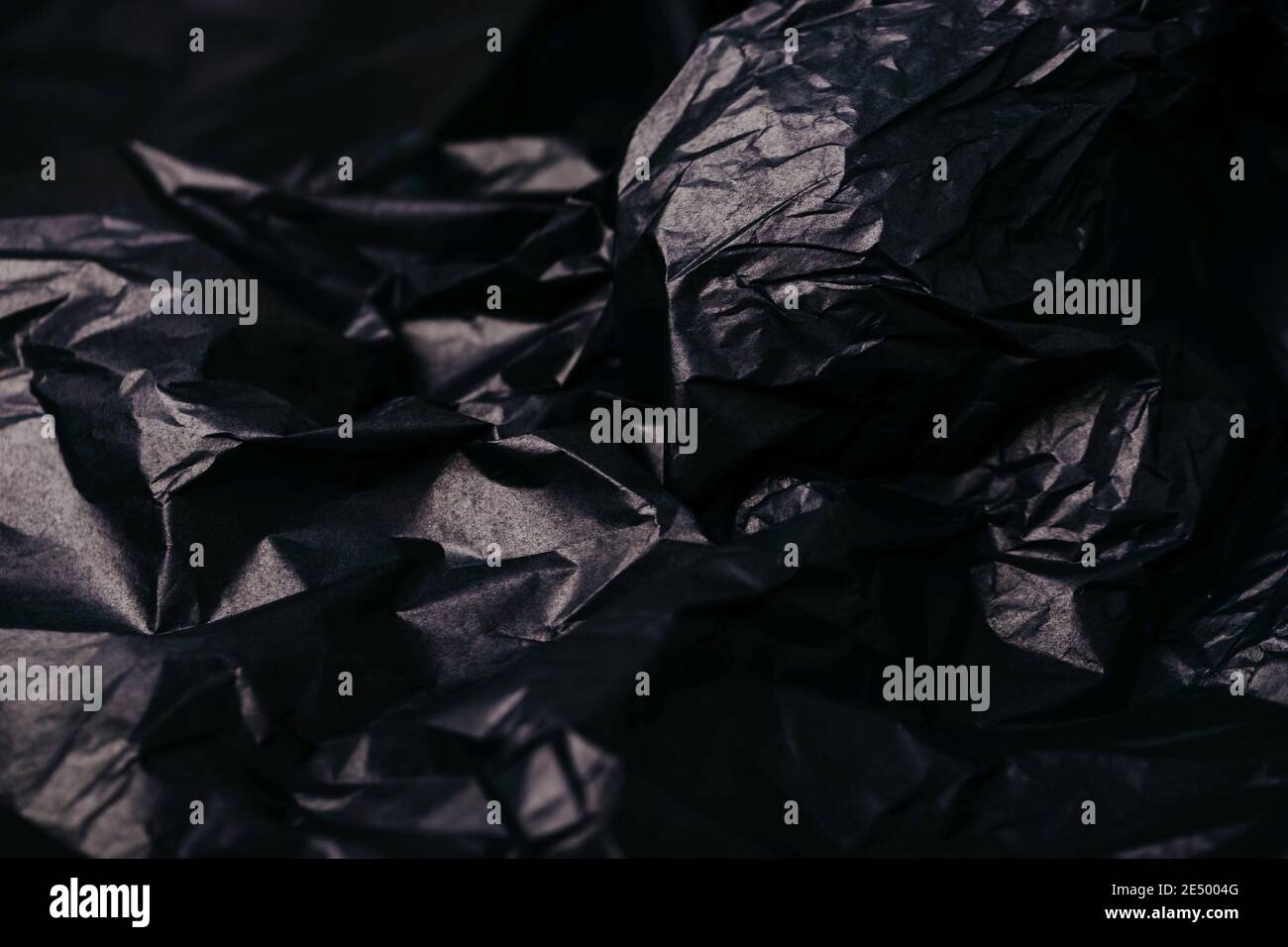 Crumpled dark black paper texture abstract background Stock Photo