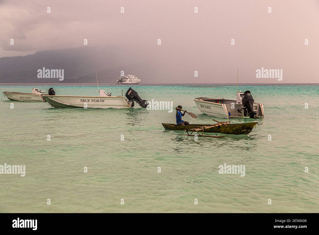 Young local surfs an outrigger canoe on Bougainville beach, Papua New Guinea Stock Photo