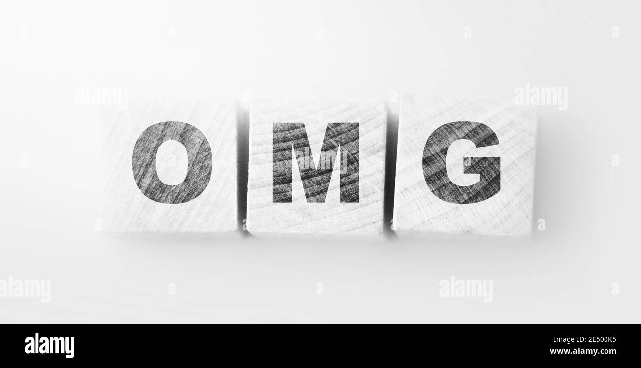 OMG written on a wooden cubes on soft pink background for Oh Mine God phrase. Stock Photo