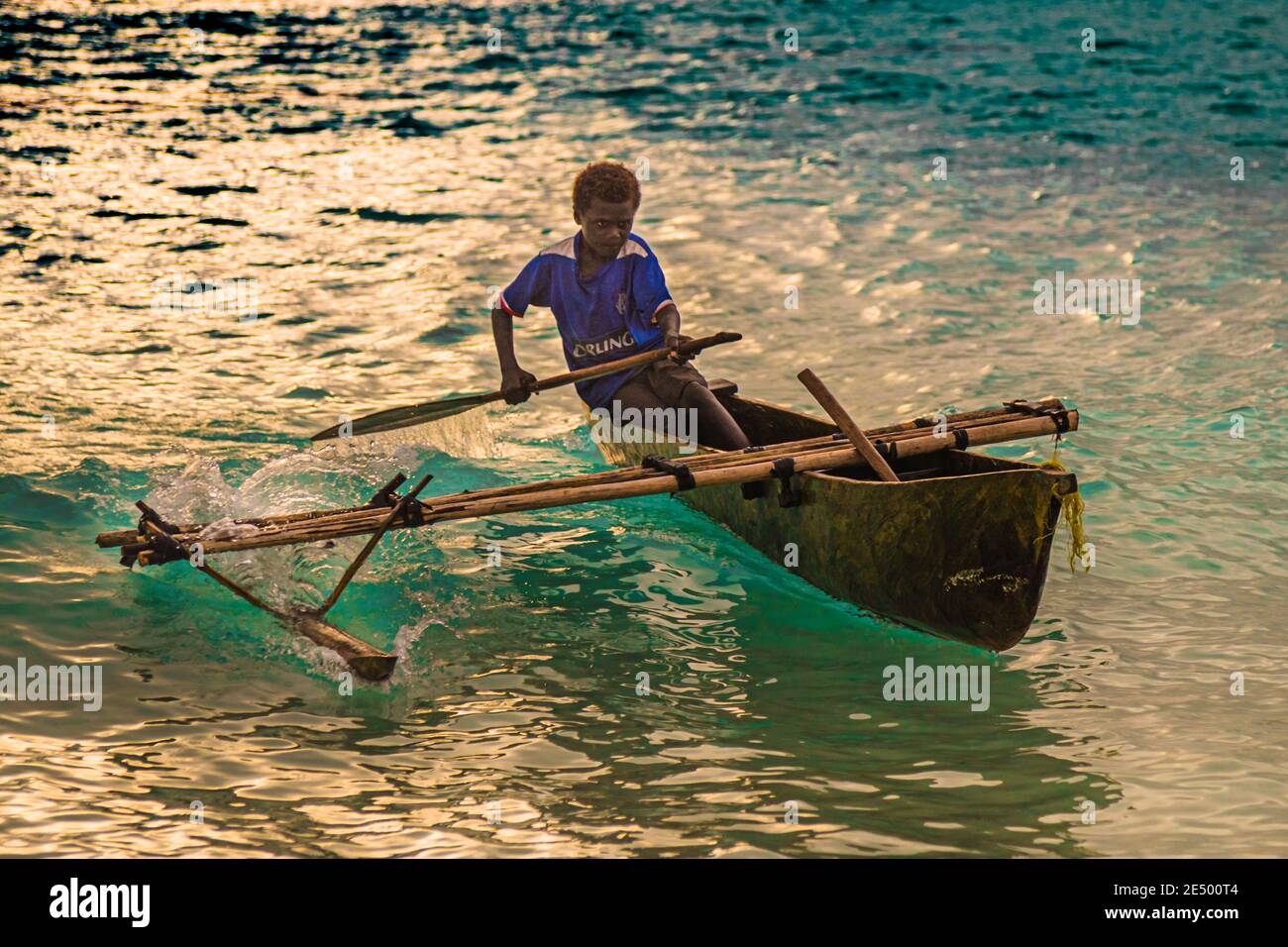 Young local surfs an outrigger canoe on Bougainville beach, Papua New Guinea Stock Photo