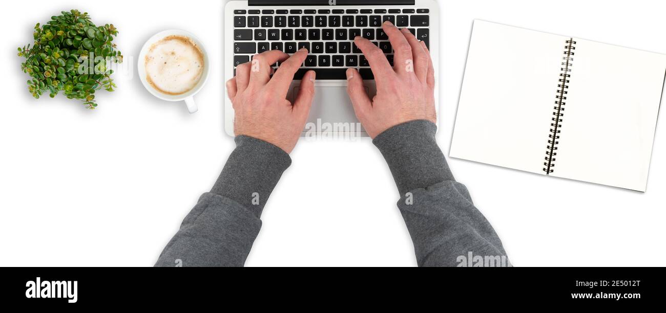 overhead view of clean white office desk with person typing on laptop computer, working from home template Stock Photo