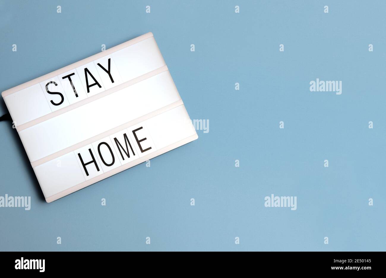 'Stay at Home' message on a lightox with a blue background with copy space. Stock Photo