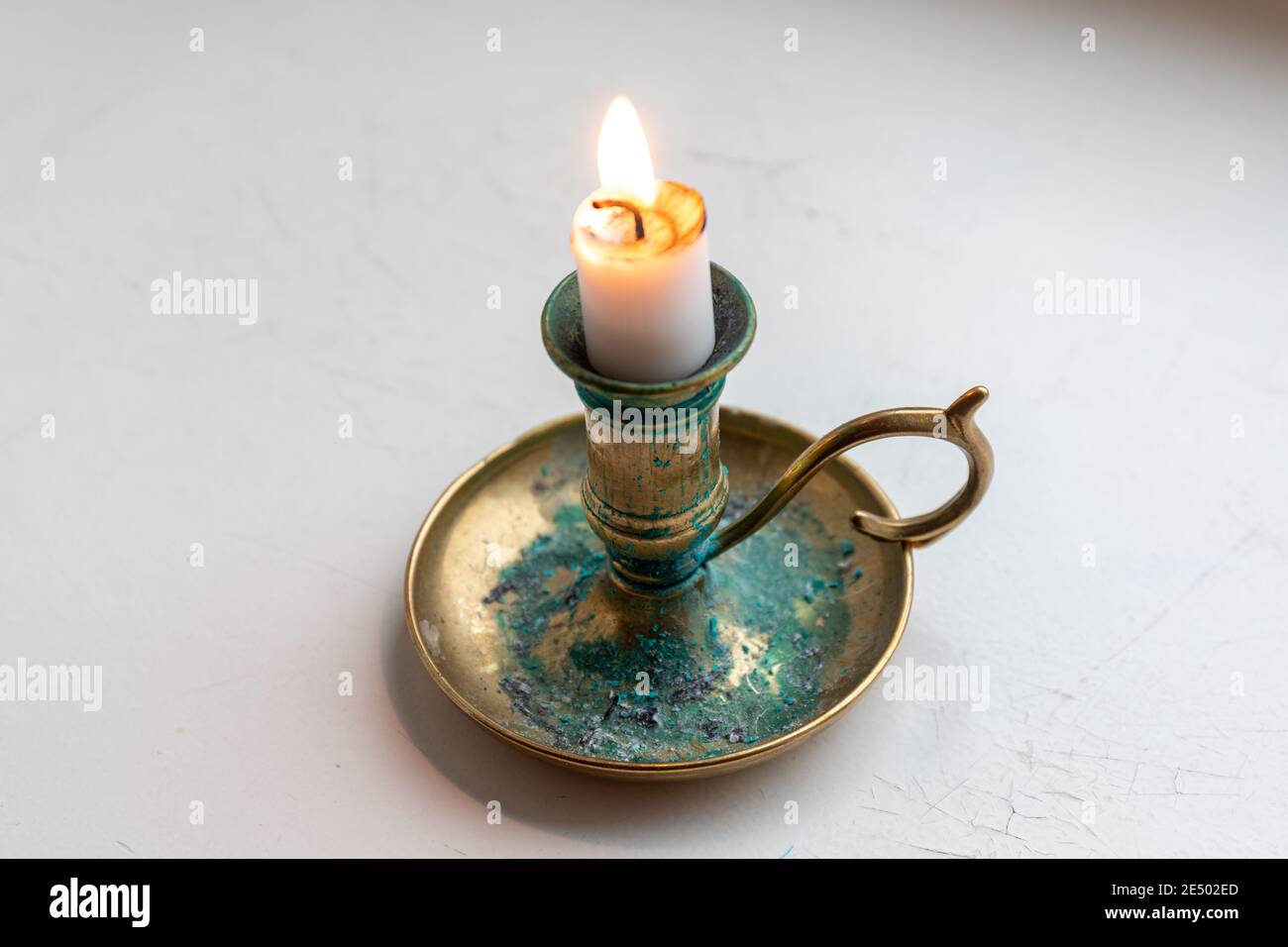 Burning candle stub on a brass candleholder or candlestick with green patina or verdigris Stock Photo