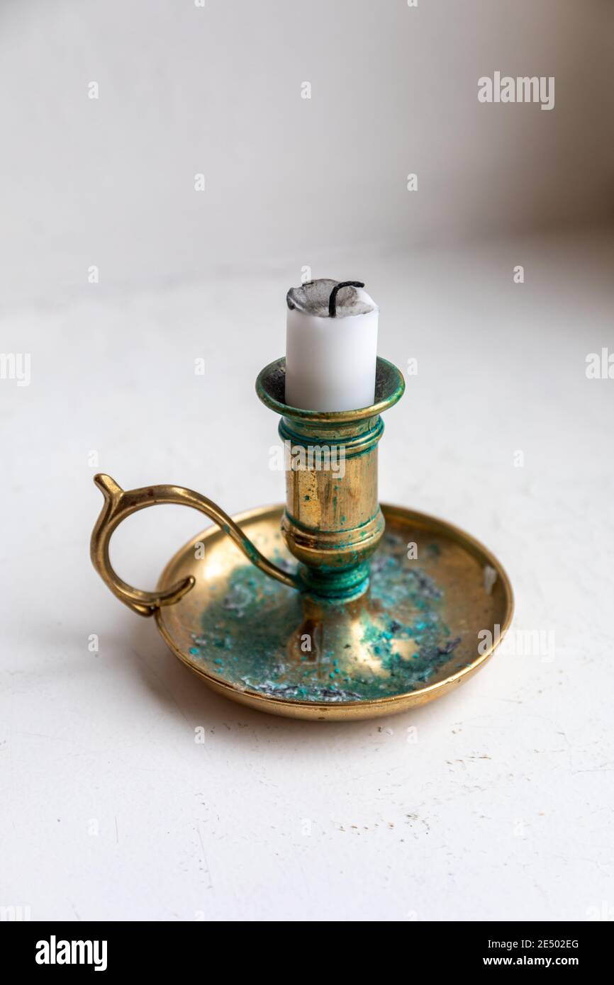 Candle stub on a brass candleholder or candlestick with green verdigris or patina Stock Photo