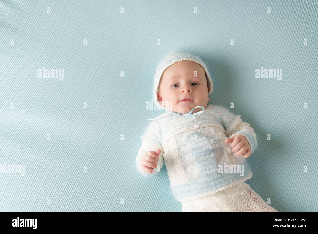 happy and smiling baby wearing blue and white suit on blue background Stock Photo