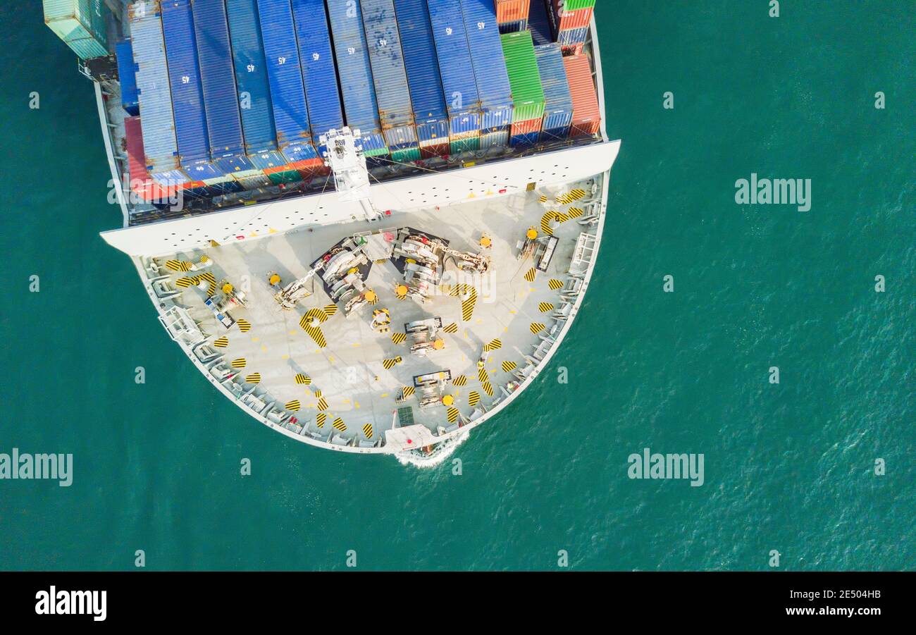 Aerial view of the bow of a container ship below passing through the Lamma shipping channel, passing Hong Kong island enroute to the cargo terminal. The Port of Hong Kong, is a deepwater seaport dominated by trade in containerised manufactured products, and to a lesser extent raw materials and passengers. A key factor in the economic development of Hong Kong, the deep waters of Victoria Harbour provide ideal conditions for berthing and the handling of all types of vessels. It is one of the busiest ports worldwide in categories of shipping movement, cargo and passengers. © Time-Snaps Stock Photo