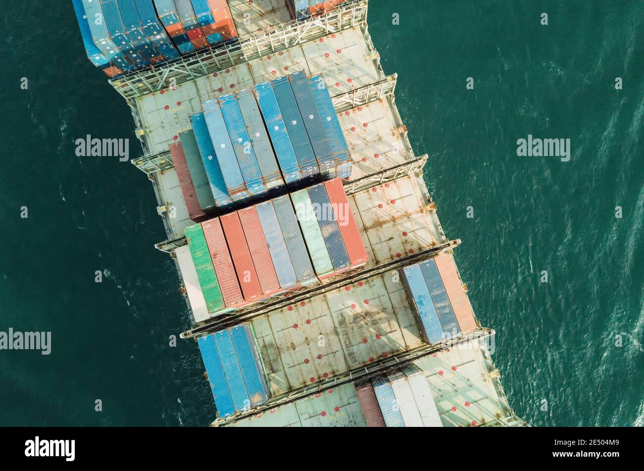 Aerial view of a containers stacked on ship below passing through the Lamma shipping channel, passing Hong Kong island enroute to the cargo terminal. The Port of Hong Kong, is a deepwater seaport dominated by trade in containerised manufactured products, and to a lesser extent raw materials and passengers. A key factor in the economic development of Hong Kong, the deep waters of Victoria Harbour provide ideal conditions for berthing and the handling of all types of vessels. It is one of the busiest ports worldwide in categories of shipping movement, cargo and passengers. © Time-Snaps Stock Photo