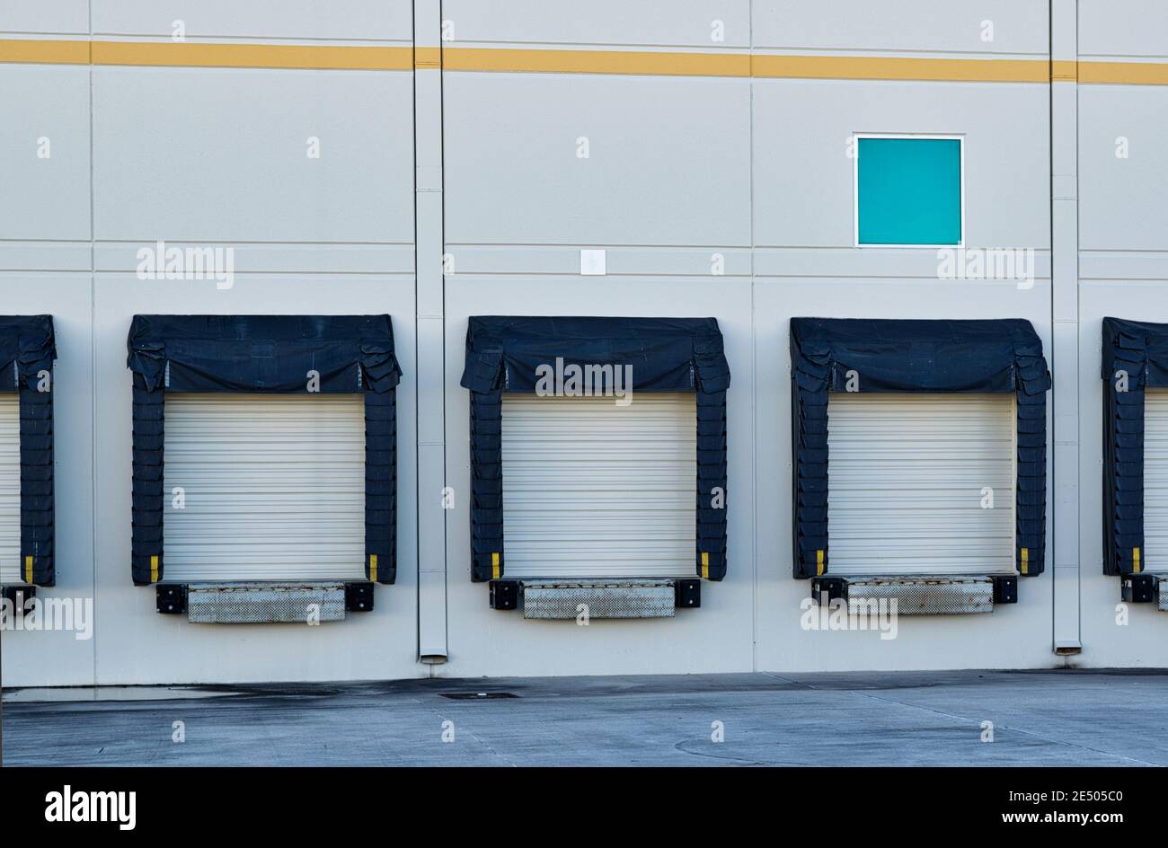 Loading dock doors at the back of a generic warehouse in an industrial district. Stock Photo