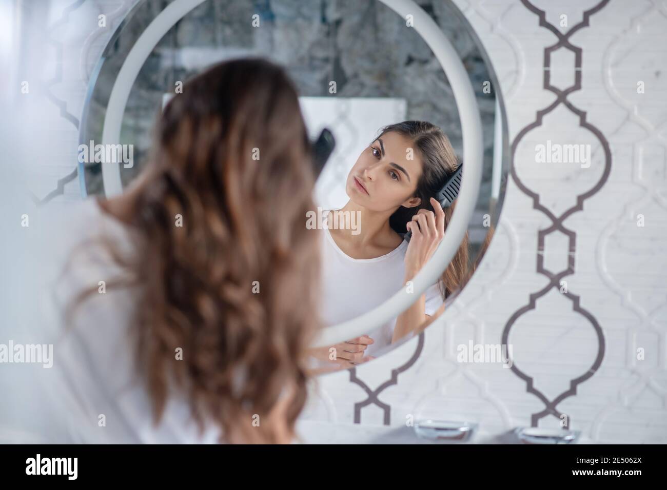 Woman combing her hair near the mirror Stock Photo