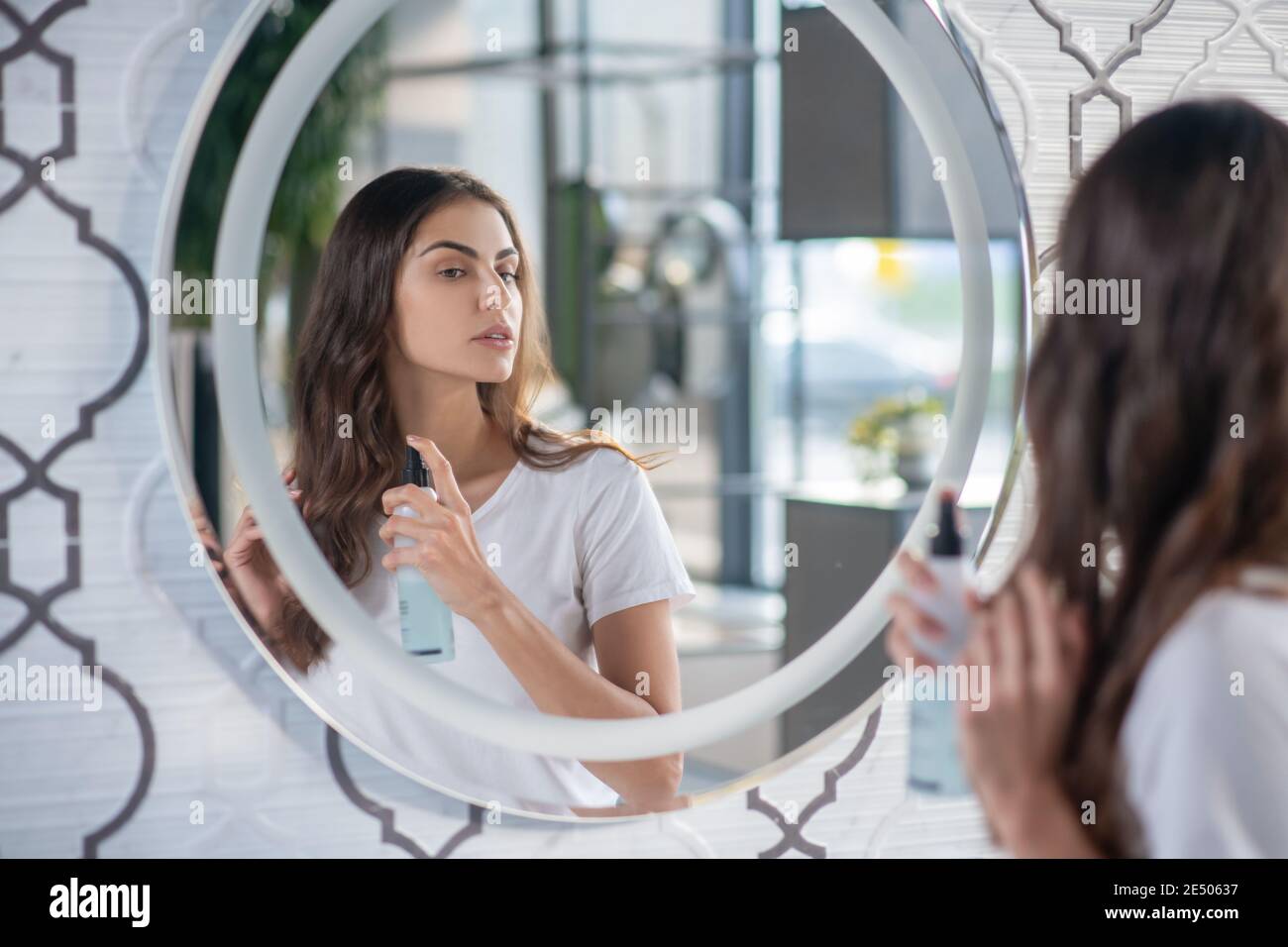Woman using a hairspray near the mirror Stock Photo