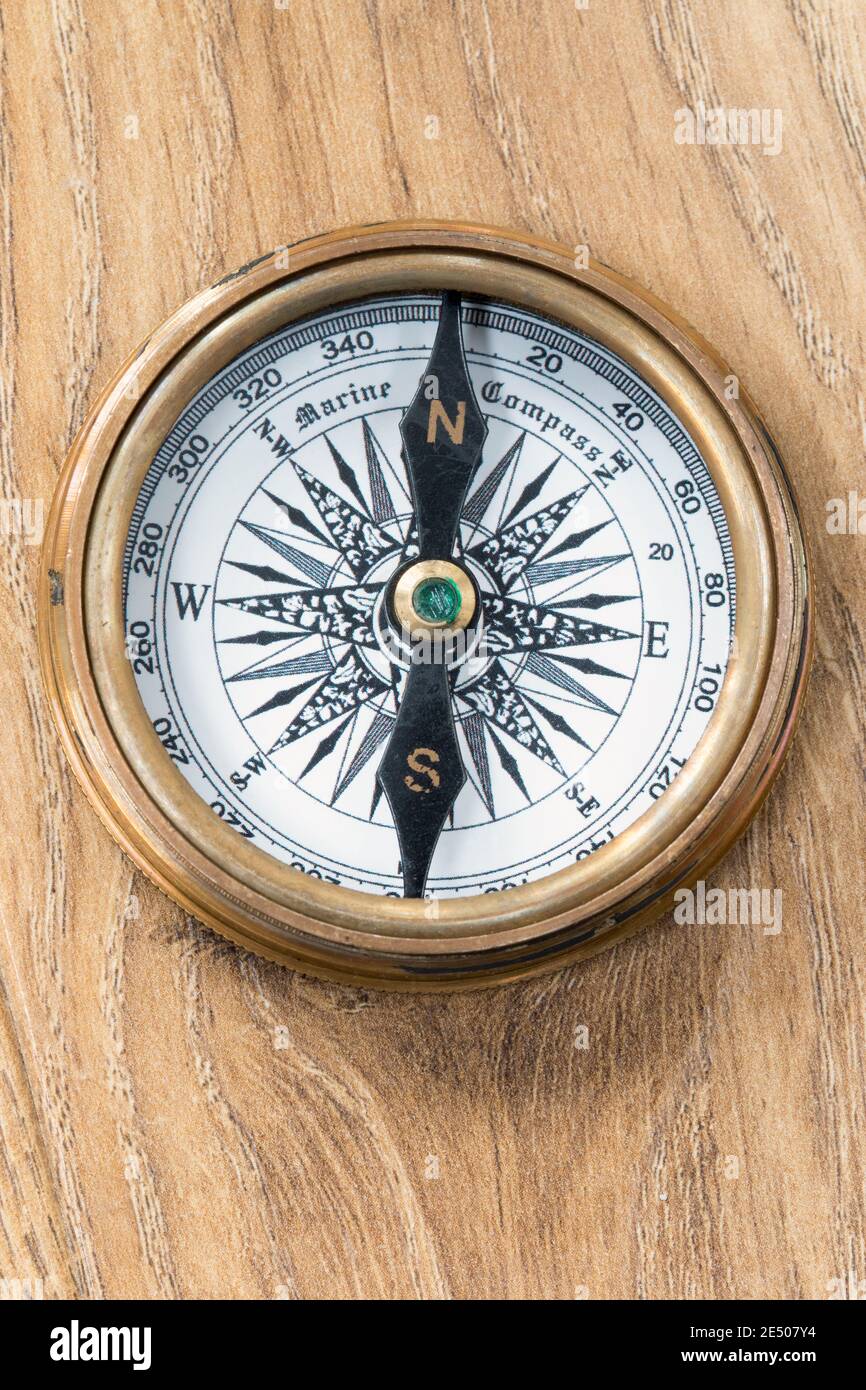 Old Fashioned compass pointing to north on a wooden deck plank