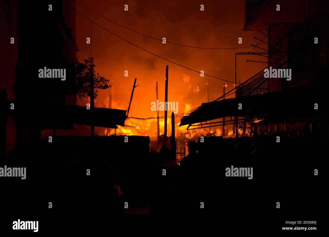 Houses, apartment, flat on fire and burning down at night in the market, slum, local center community, downtown in the big city. Asian cityscape. Stock Photo