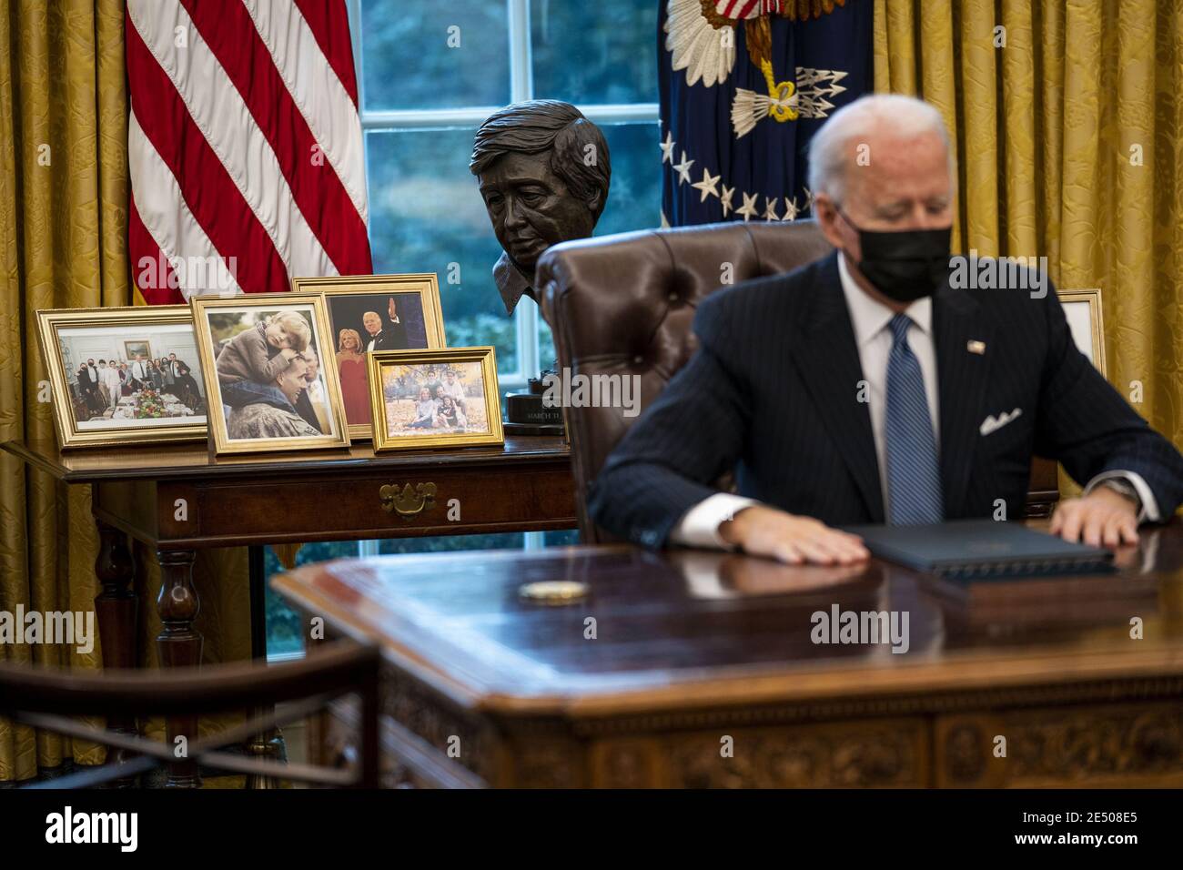 Washington, United States. 25th Jan, 2021. Family pictures are seen behind President Joe Biden as he signs an executive order reversing a Trump era ban on transgender serving in the military, in the Oval Office at the White House, Monday, January 25, 2021in Washington, DC. Pool Photo by Doug Mills/UPI Credit: UPI/Alamy Live News Stock Photo