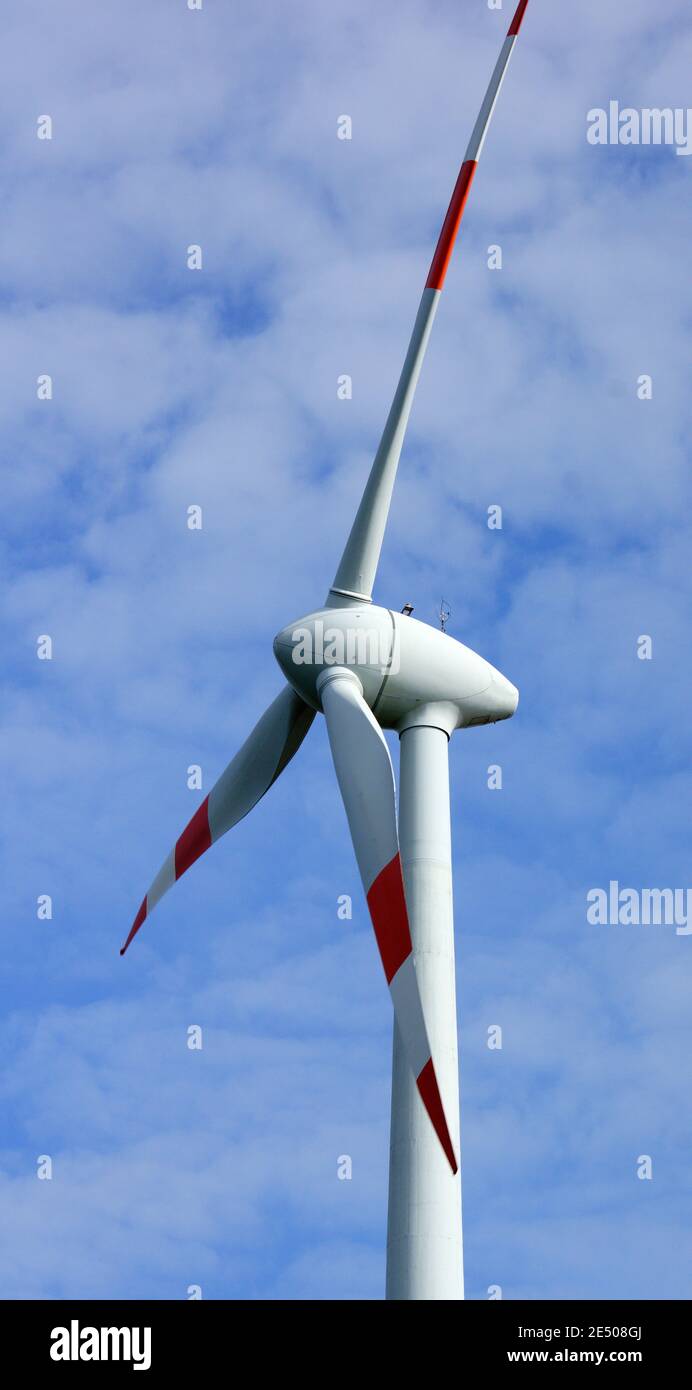 Close-up of a wind turbine creating alternative energy. Blue sky with clouds. Wind mill or wind-turbine. Stock Photo