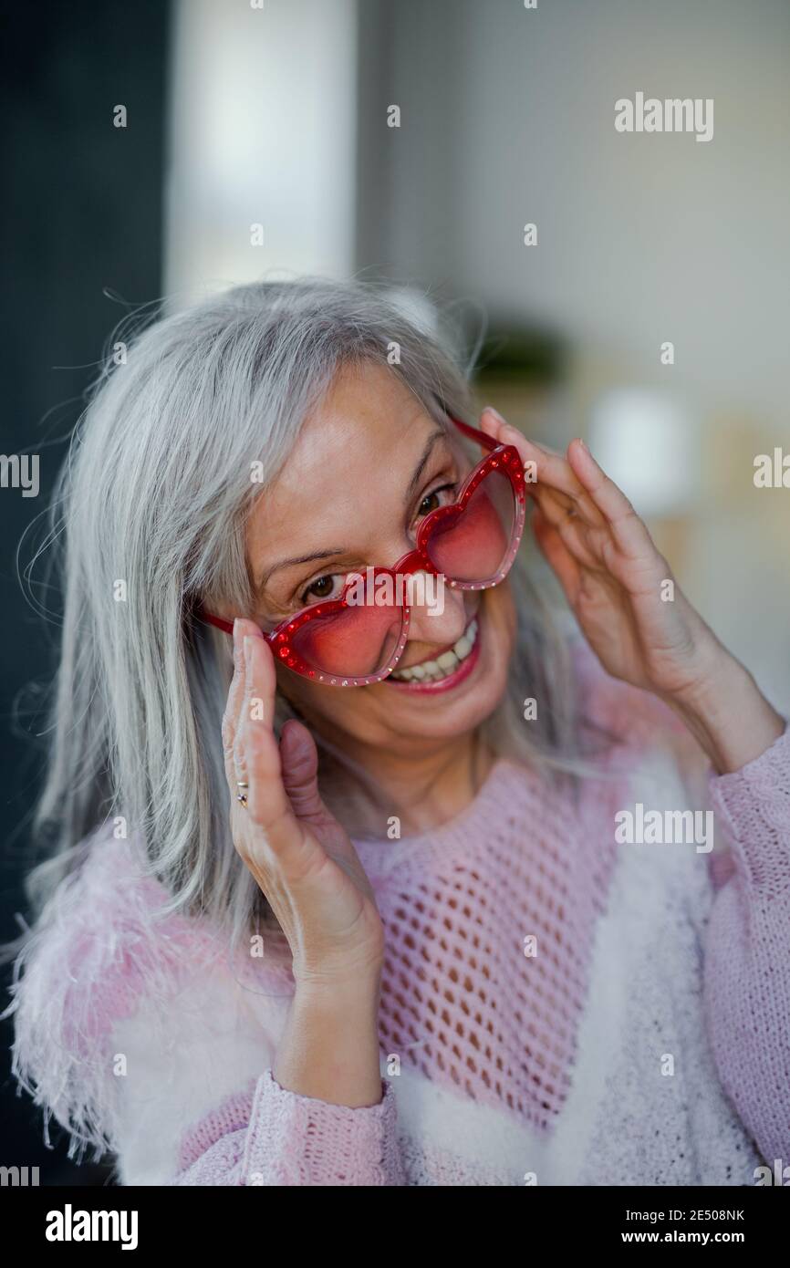 Portrait of senior woman with sunglasses indoors at home, laughing. Stock Photo