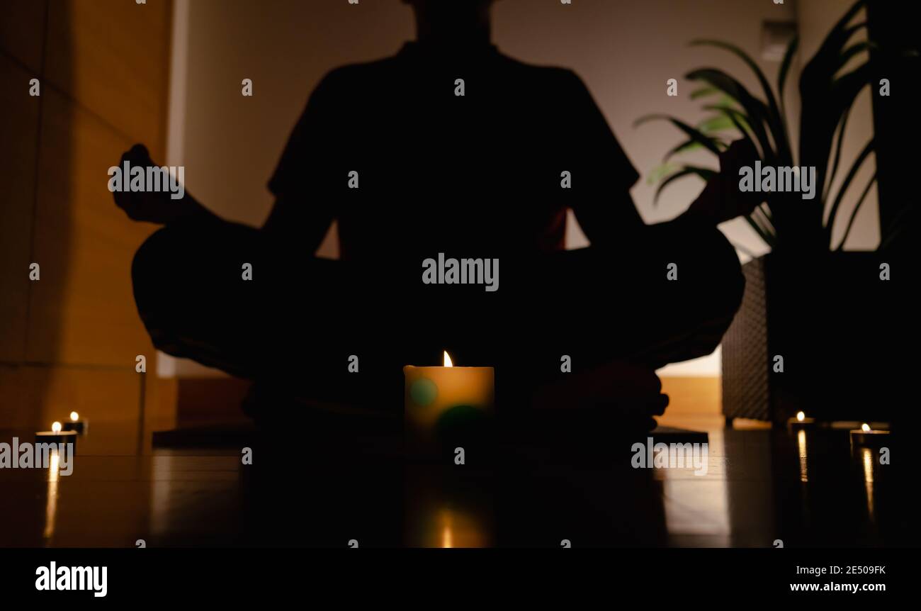 Relaxed person sitting on the yoga mat with legs crossed and meditating ...