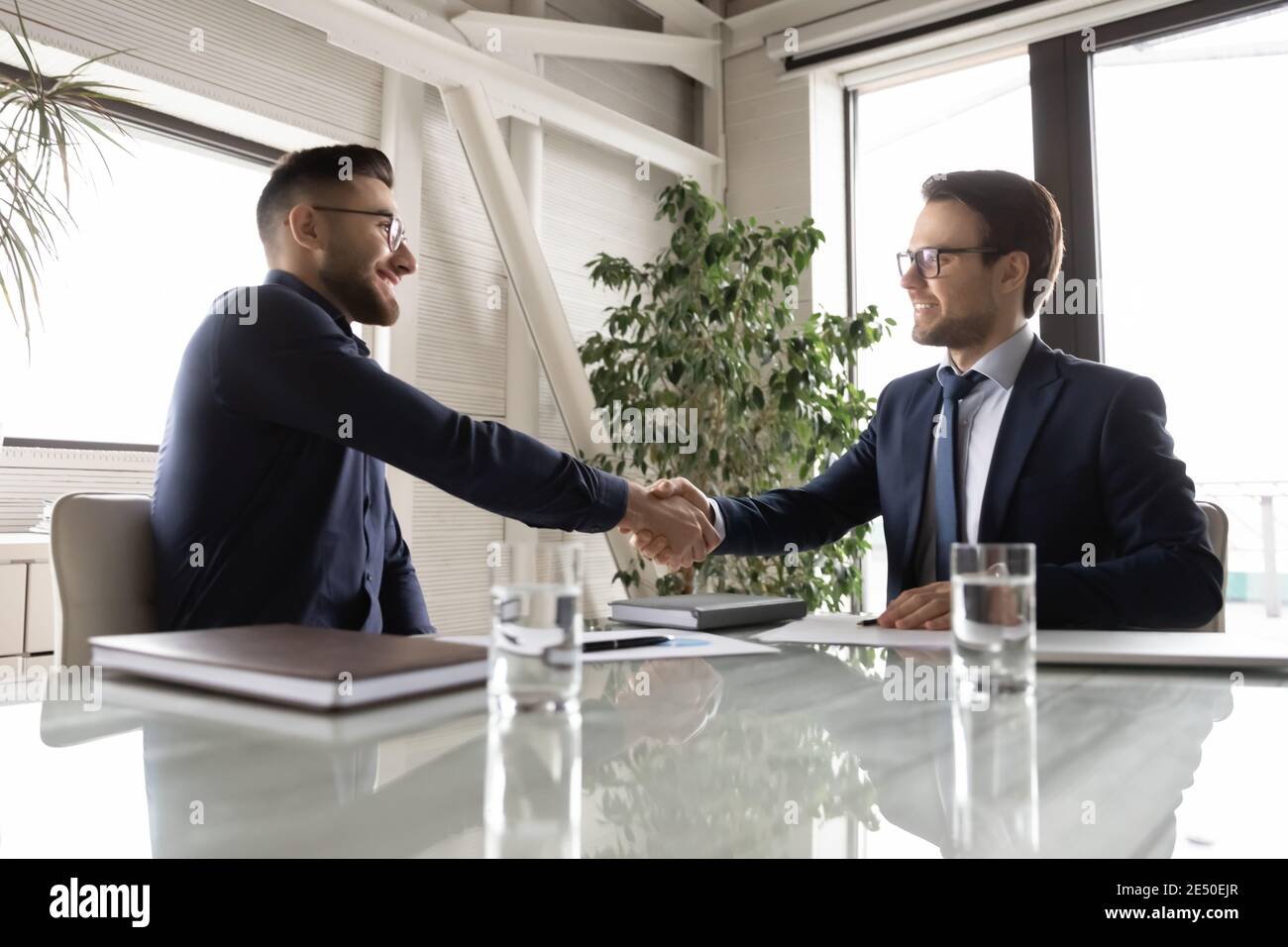 Side view happy diverse business partners shaking hands, making deal Stock Photo