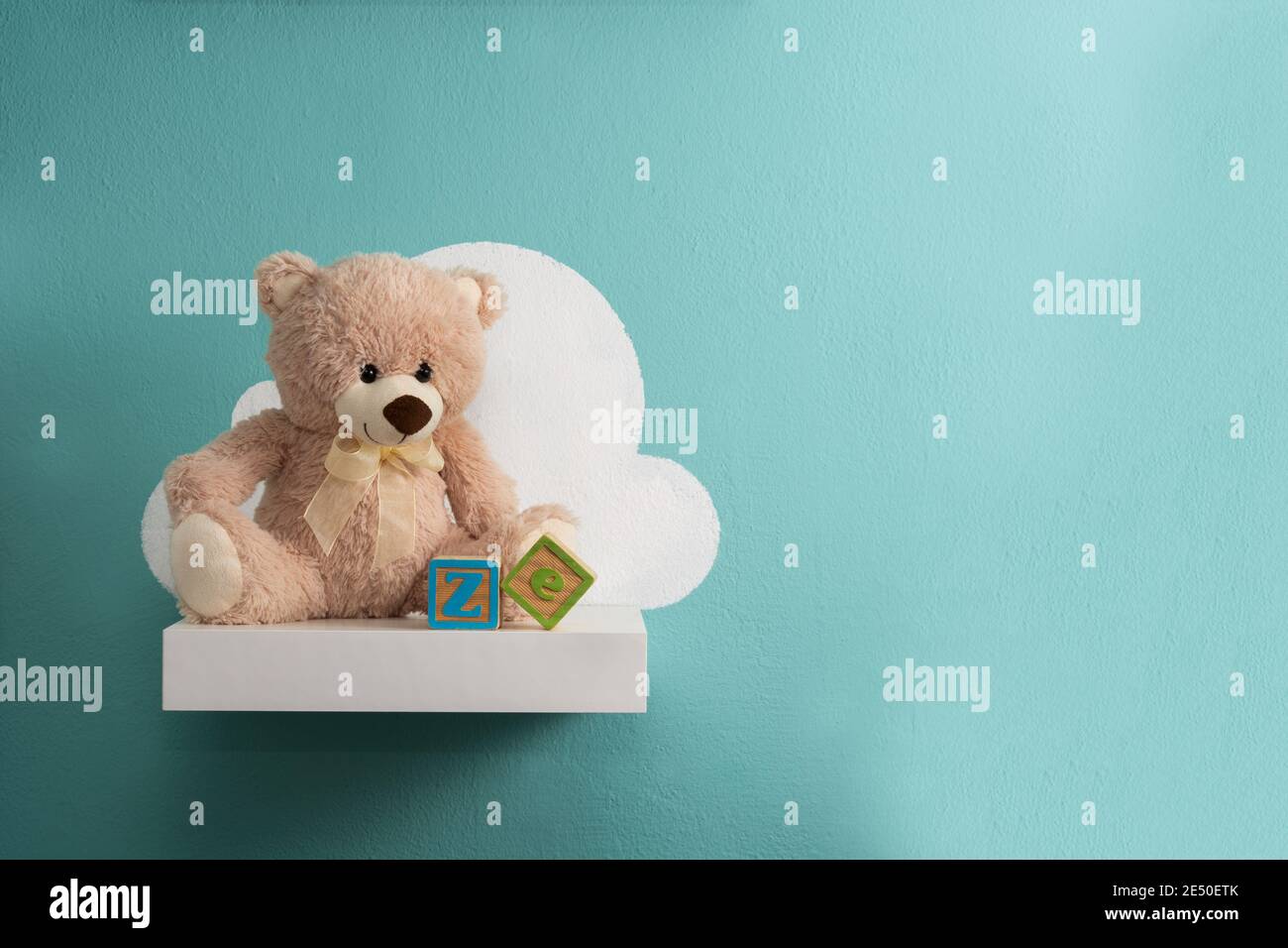 Teddy bear on white shelf and turquoise wall Stock Photo