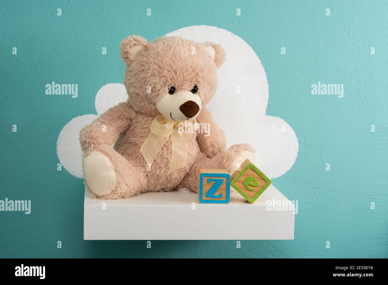 Teddy bear on white shelf and turquoise wall Stock Photo