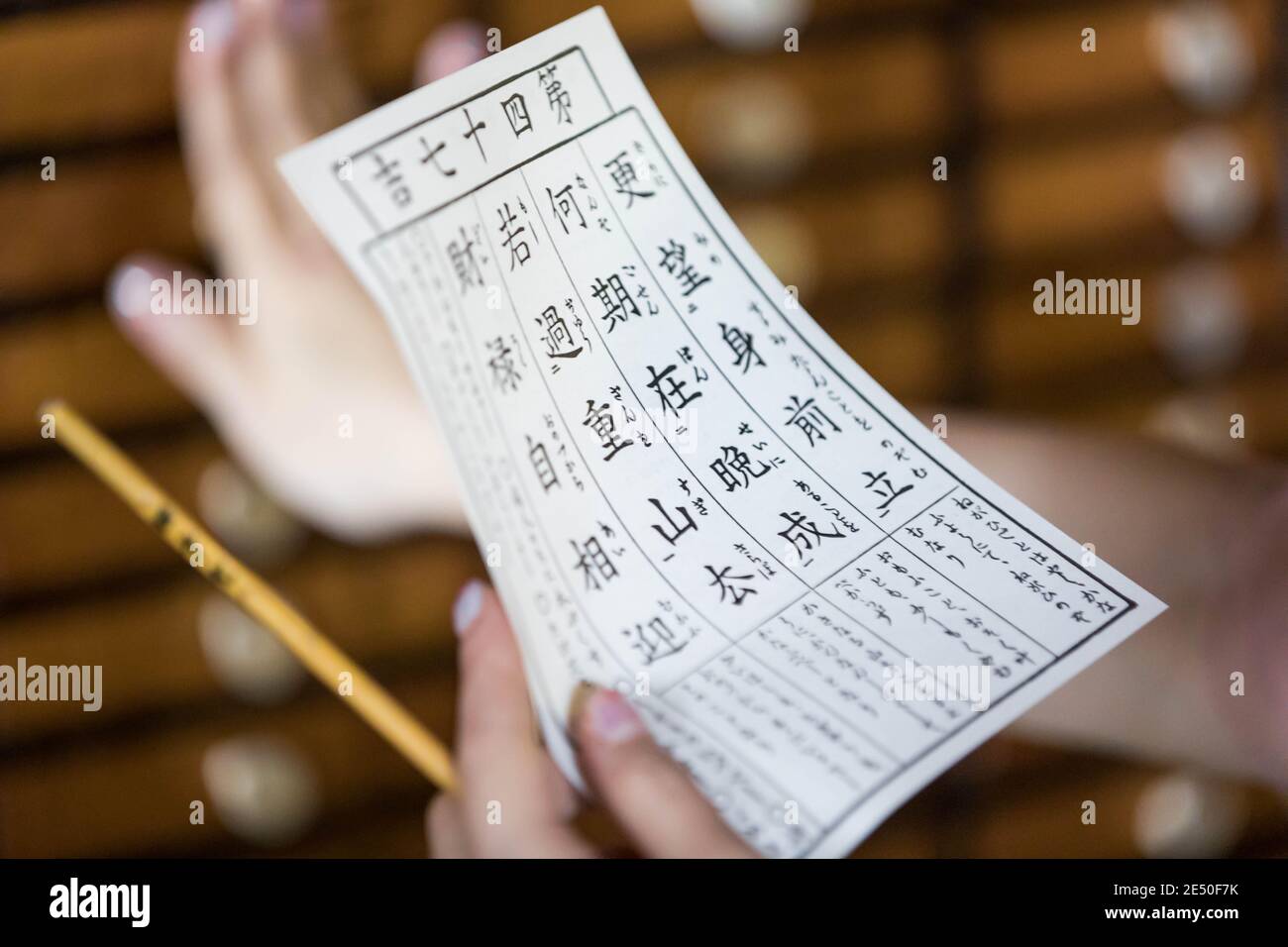 Close up of female hands holding a fortune-telling note against a bokeh background Stock Photo