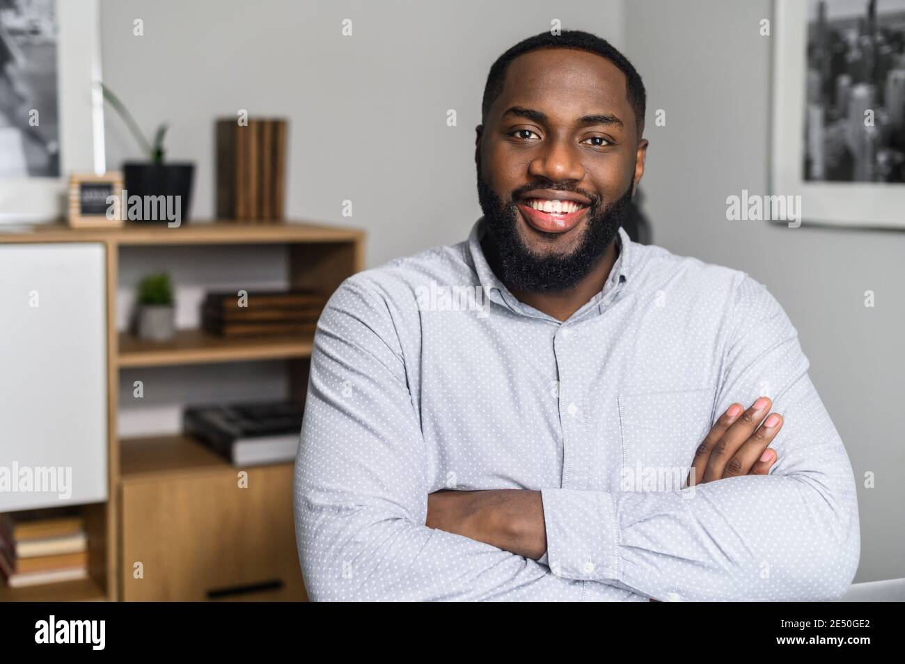 Happy African-American company leader CEO standing with his arms crossed in the office. Portrait of a successful smiling entrepreneur, confidently Stock Photo