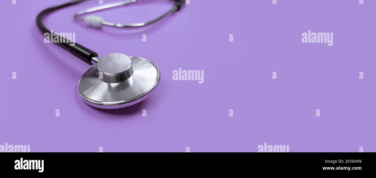 Black stethoscope on a purple background with copy space. Stock Photo