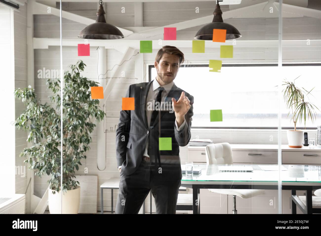 Confident businessman working on project plan, looking at sticky papers Stock Photo