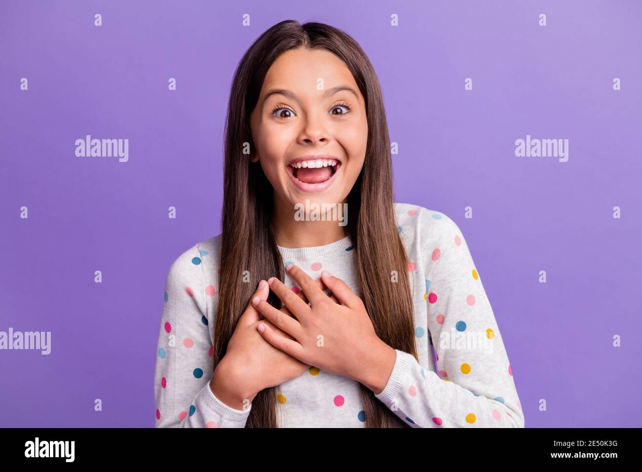 Photo portrait of laughing girl touching chest with hands isolated on vivid violet colored background Stock Photo
