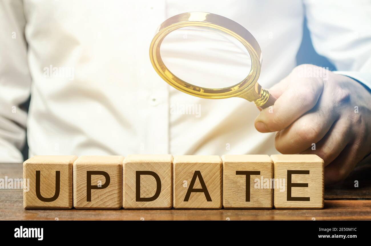 Wooden blocks with the word Update and a magnifying glass. Updating the version or software components / program. New data and information. Notificati Stock Photo