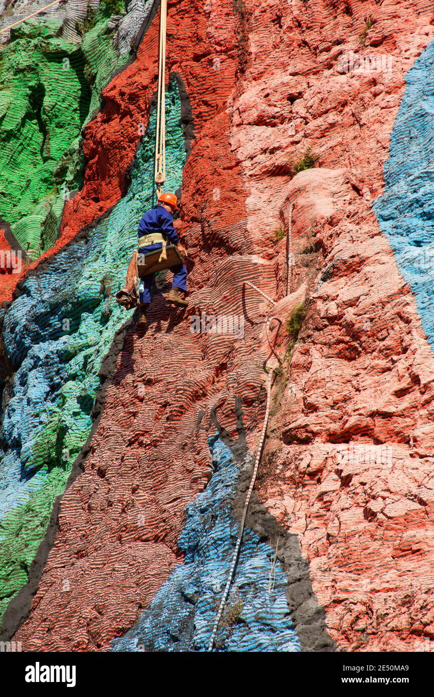 Prehistoric Rope Workman hanging from ropes, restoring paintwork of Mural de la ...