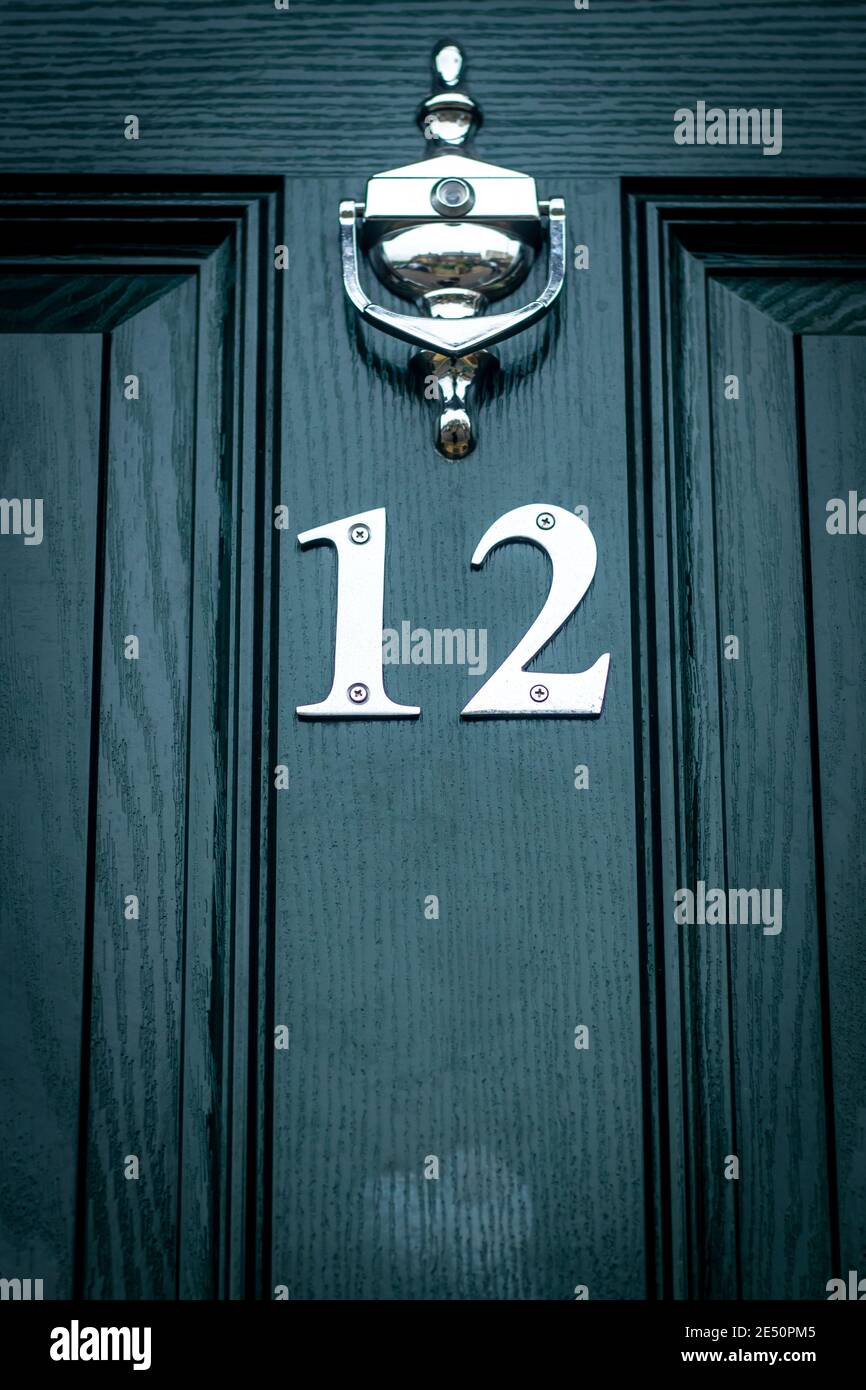 Twelve in silver metal digits on  dark green wooden front door in London, England Stock Photo