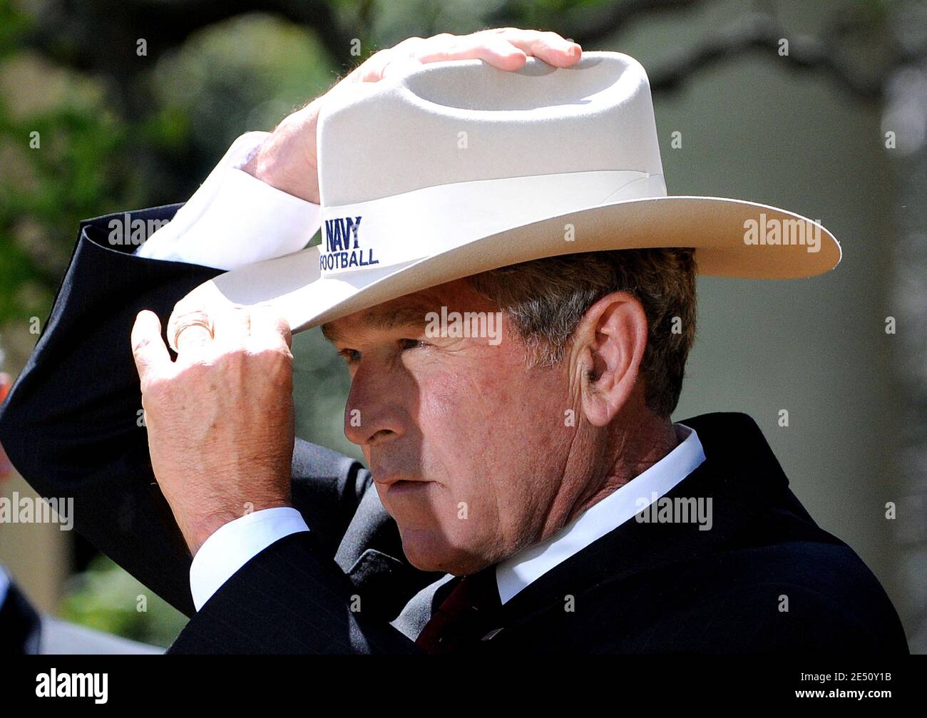 US President George W. Bush tries on a cowboy hat given to him by members  of the United States Naval Academy football team during a ceremony to  present the Commander-in-Chief's Trophy to