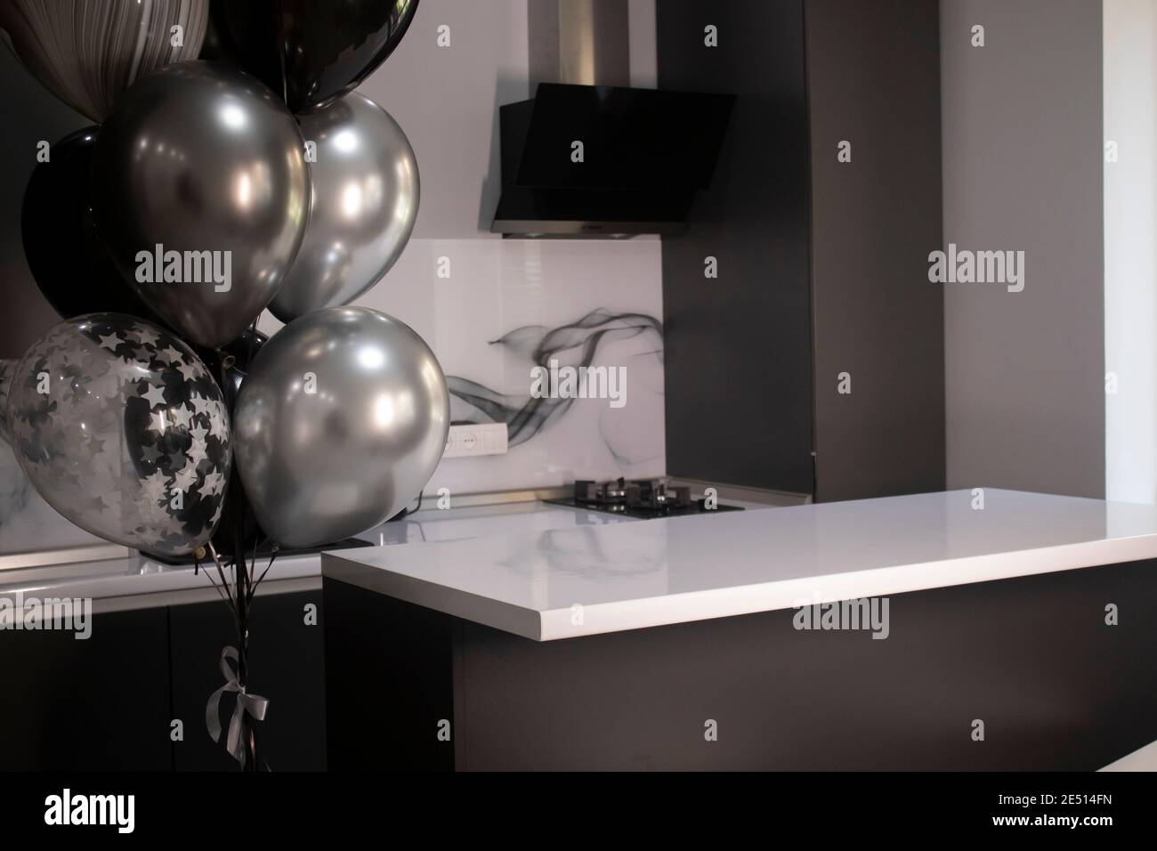 https://c8.alamy.com/comp/2E514FN/corner-of-stylish-minimalistic-grey-kitchen-dark-gray-cupboards-white-countertops-and-bar-black-and-white-balloons-high-quality-photo-2E514FN.jpg