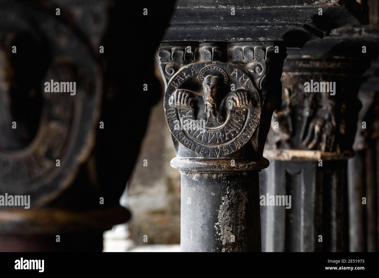 Close up of medieval black carved stone capitol in a northern Italian cloister Stock Photo