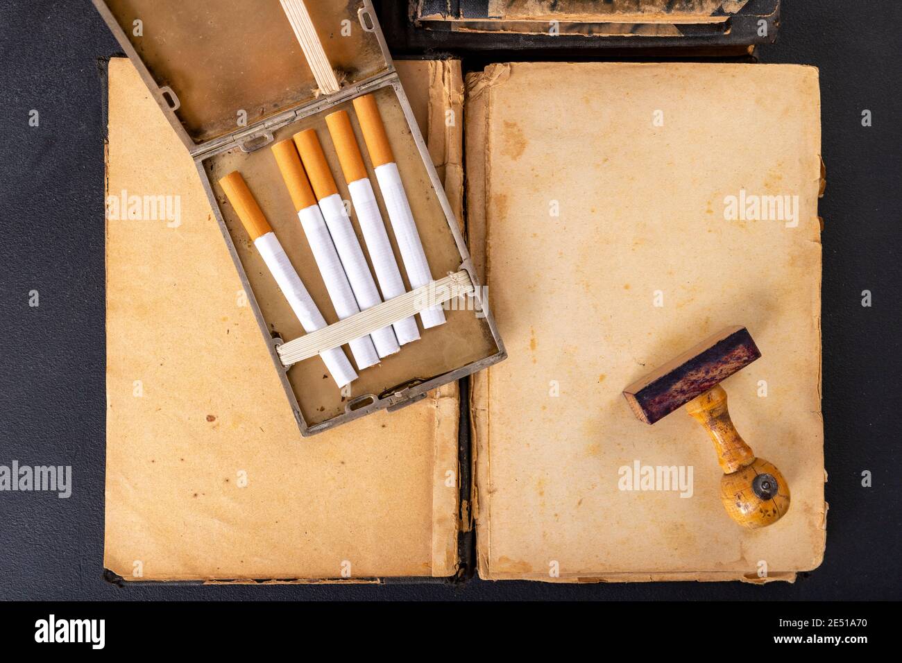 Wooden stamp for stamping and cigarettes in a metal cigarette case. Office  accessories in the old office. Dark background Stock Photo