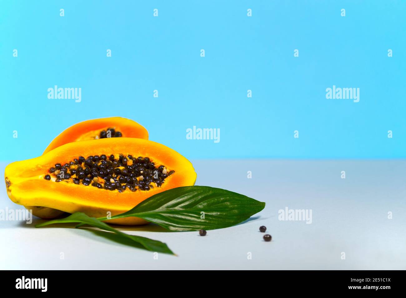 Two Half of Papaya with Green and Seeds on Blue Background, Minimalism