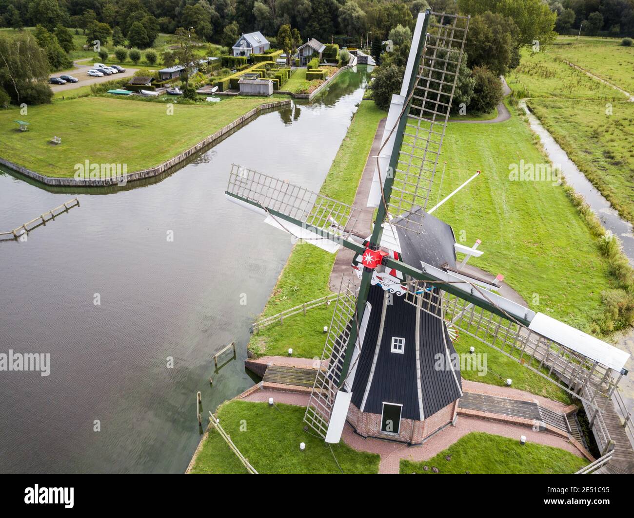 Aerial wide angle view of a dutch landscape, with meadows, canals and an ancient black and white windmill in the foreground Stock Photo