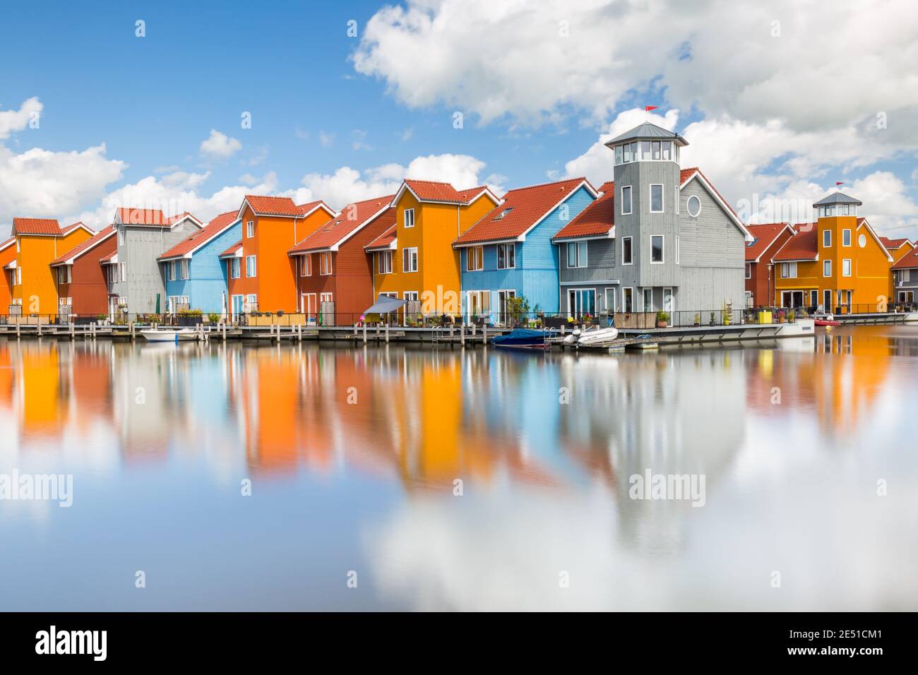 Symmetrical close up of a group of colorful modern dutch water-front houses, under a blue summer sky with puffy clouds Stock Photo