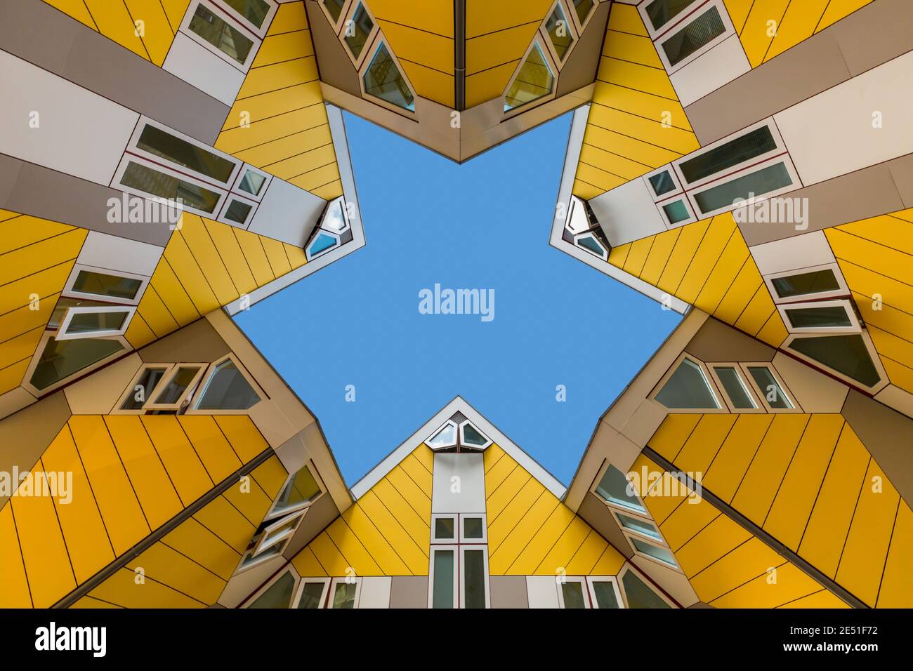 Symmetrical and geometrical wide angle view of a group of modern yellow houses, as seen from below, against a solid blue summer sky Stock Photo