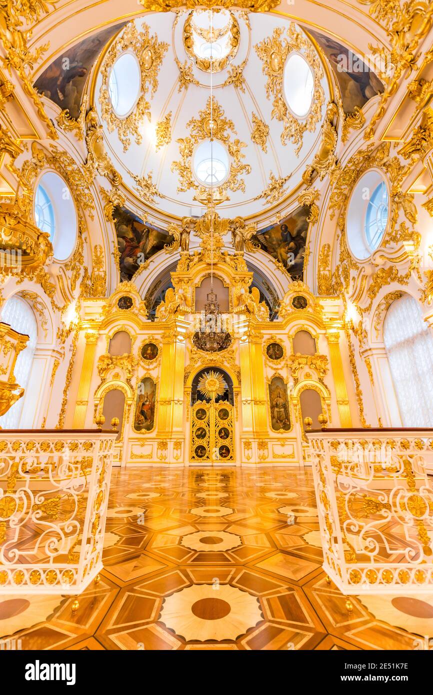 Wide angle view of a lavishly adorned chapel in the Ermitage Winter Palace, with baroque gold plated plaster reflecting on the hardwood floor Stock Photo