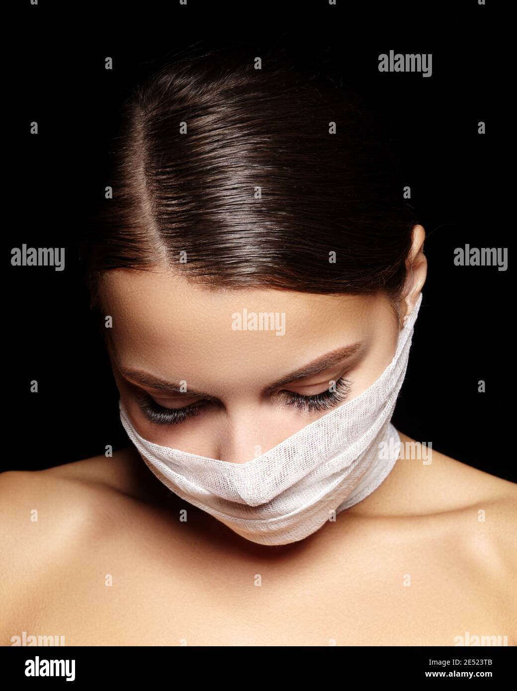 Beautiful woman with a bandage mask on face. Fashion eye make-up. Beauty plastic surgery or protection hygiene in viral covid-19 pandemic Stock Photo