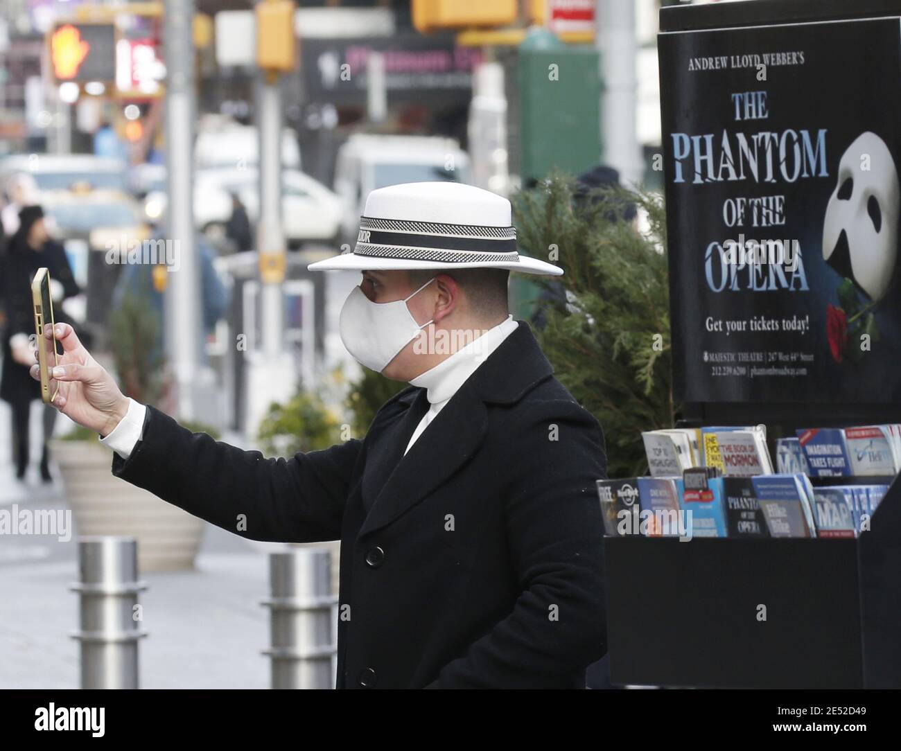 New York, United States. 25th Jan, 2021. A man takes a photo near a poster for the Broadway show Phantom Of The Opera as Times Square remains quiet of pedestrian and automobile traffic due to the coronavirus pandemic in New York City on Monday, January 25, 2021. Photo by John Angelillo/UPI Credit: UPI/Alamy Live News Stock Photo