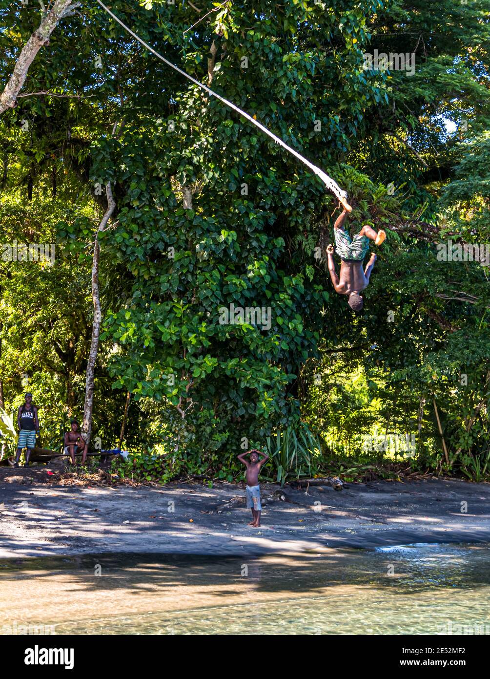 Tarzan exercise with jumping into shallow water on the beach in Bougainville, Papua New Guinea Stock Photo