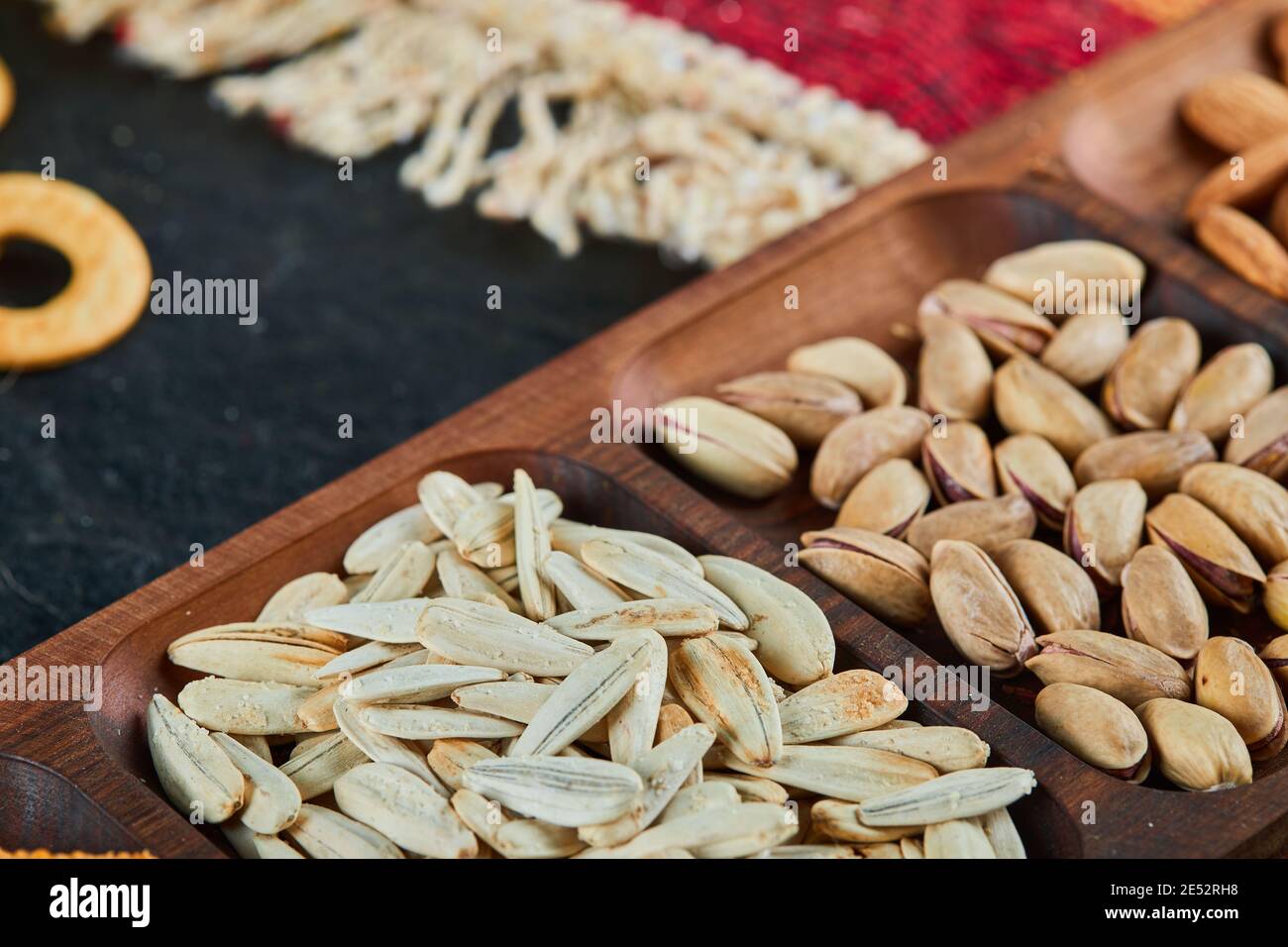 Pistachios, almonds and sunflower seeds on wooden plate Stock Photo