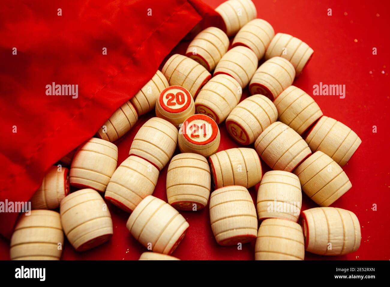 Wooden bingo kegs, on a red background in a red bag, for playing bingo. A way to spend time at home. 2021 Stock Photo