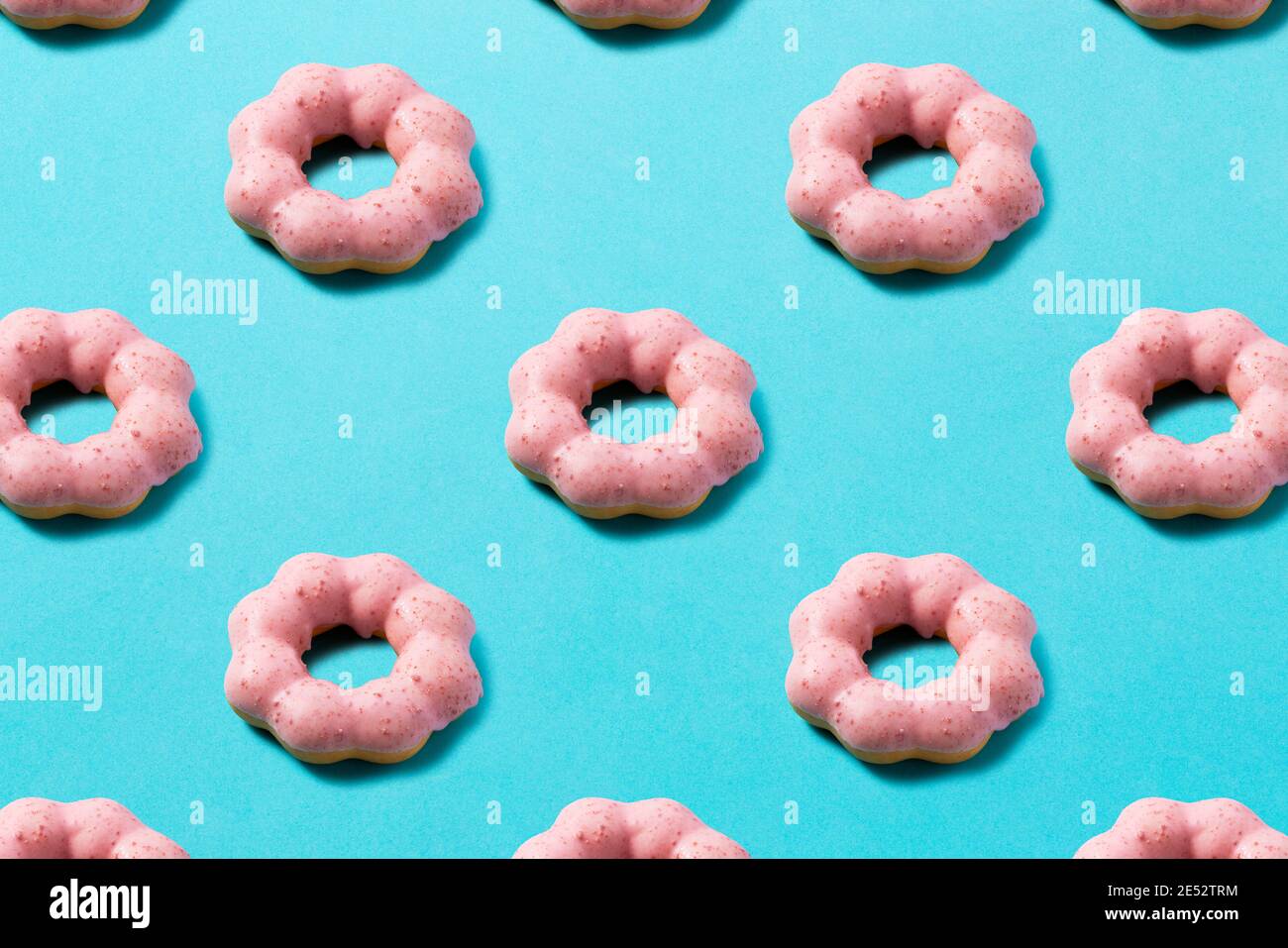 Pink donuts lined up regularly on a blue background. Background material Stock Photo