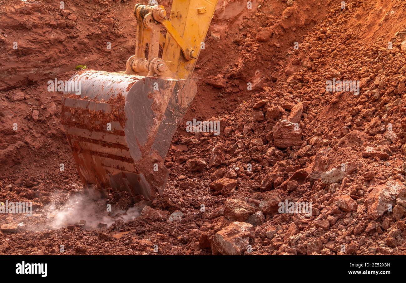 Backhoe bucket digging the soil at agriculture farm to make pond. Crawler excavator digging at shale layer. Excavating machine. Earth moving equipment Stock Photo
